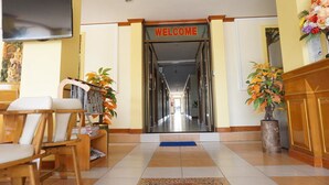 A reception area with a 'WELCOME' sign, a television, seating, and potted plants. - Phimaibury Apartment (Phimai)