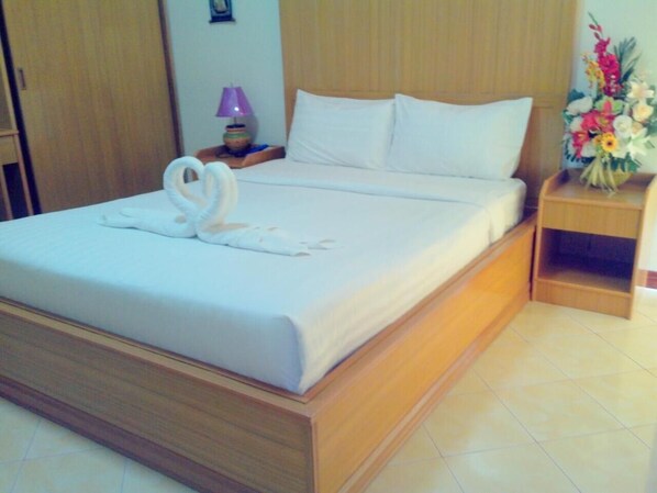 A neatly made bed with white linens and a decorative swan pillow. - Phimaibury Apartment (Phimai)