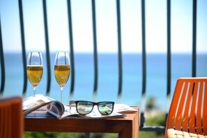 Two glasses of white wine on a wooden table with a pair of sunglasses and a magazine, overlooking a scenic view of the ocean. - Kenting Coast Resort (Hengchun)