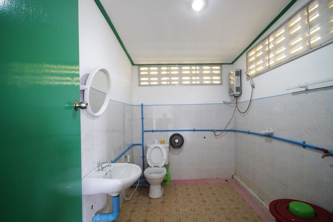 A small, basic bathroom with a toilet, sink, and shower.