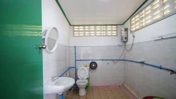 A small, basic bathroom with a toilet, sink, and shower.