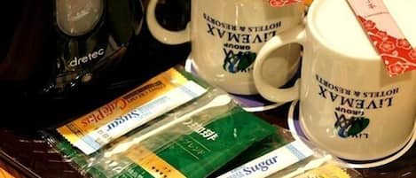 A tray with two white mugs labeled 'LIVEMAX' and a tea kettle, along with several packets of sugar and a 'CafePlus' product.