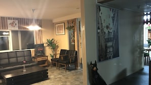 Un saló amb un sofà, cadires, una llar de foc i un gos.