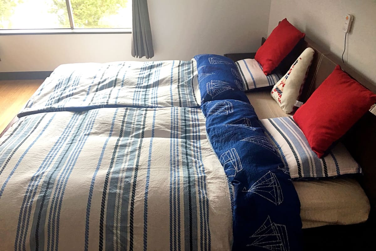A bed with striped bedding, red and white pillows, and a window with curtains.