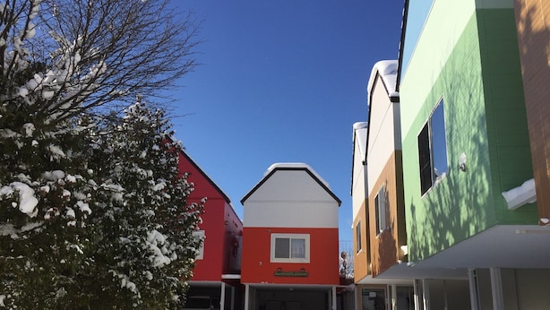 Hotel amb façana vermella i blanca, zona de pàrquing coberta i terra coberta de neu.