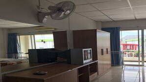 A hotel room with a large bed, a desk with a computer, a TV, and a fan. - Eve Place Pattaya (Pattaya)