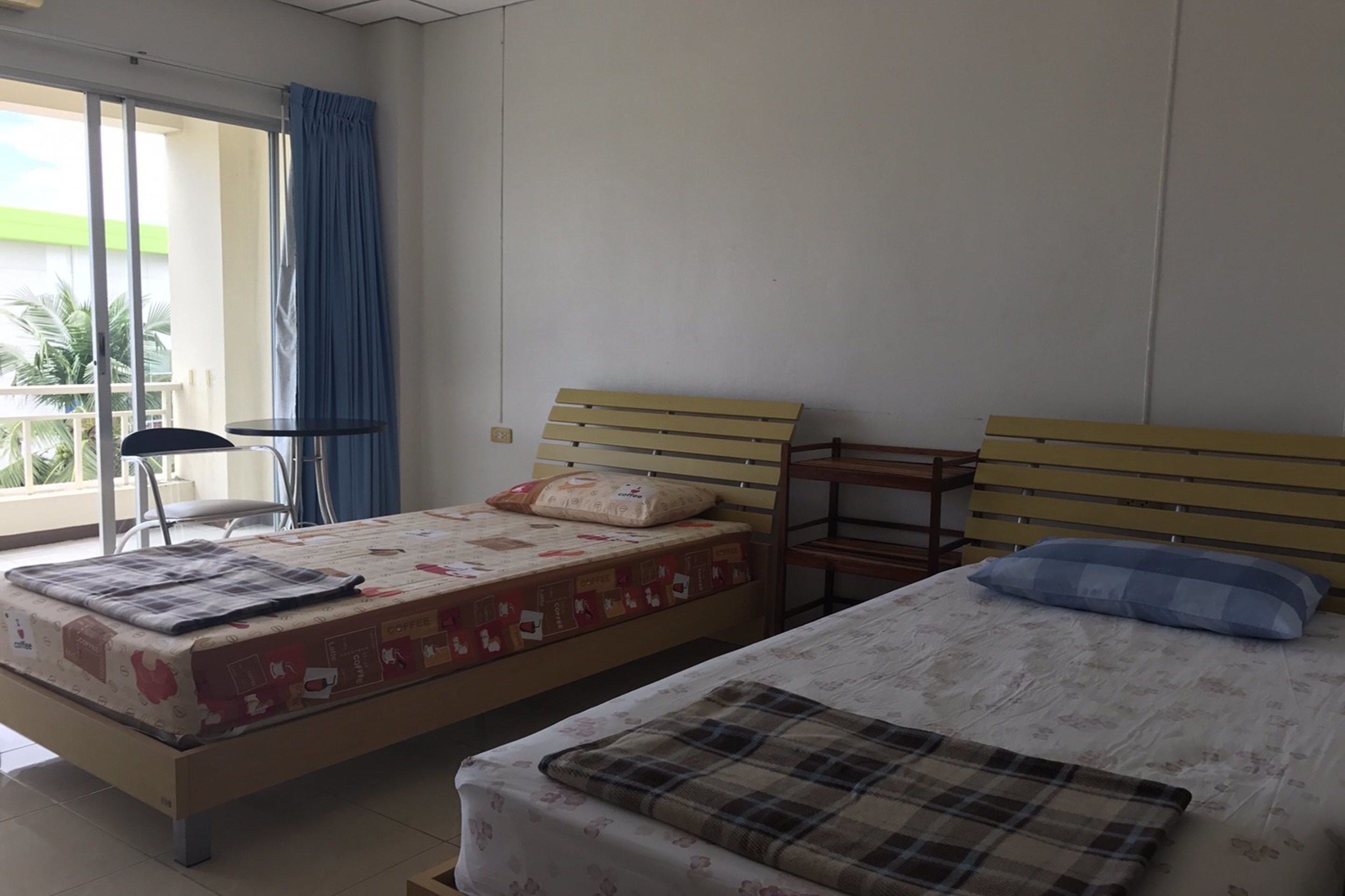 A bedroom with two beds, a chair, and a table.