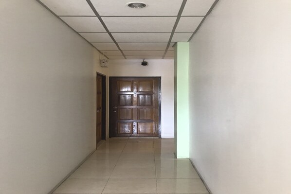 Un pasillo con suelo de baldosas que lleva a una puerta de madera.