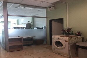 A laundry area with a washing machine, a shelf unit, and a large window. - Eve Place Pattaya (Pattaya)