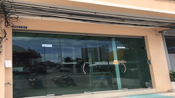 A building with a large glass entrance, a welcome sign, and a street view reflection. - Eve Place Pattaya (Pattaya)