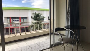A balcony with a view of a building labeled 'BOOKS' and a palm tree. There are two chairs and a small table on the balcony. - Eve Place Pattaya (Pattaya)