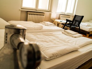 A hotel room with two beds, a table with a chair, and a radiator. - Lobagola B&B (Zagreb)