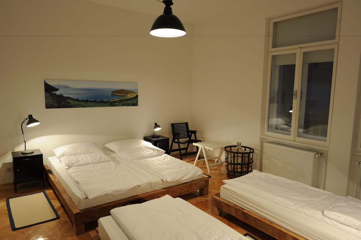 A room with two wooden beds, a desk, a chair, a radiator, and a window.