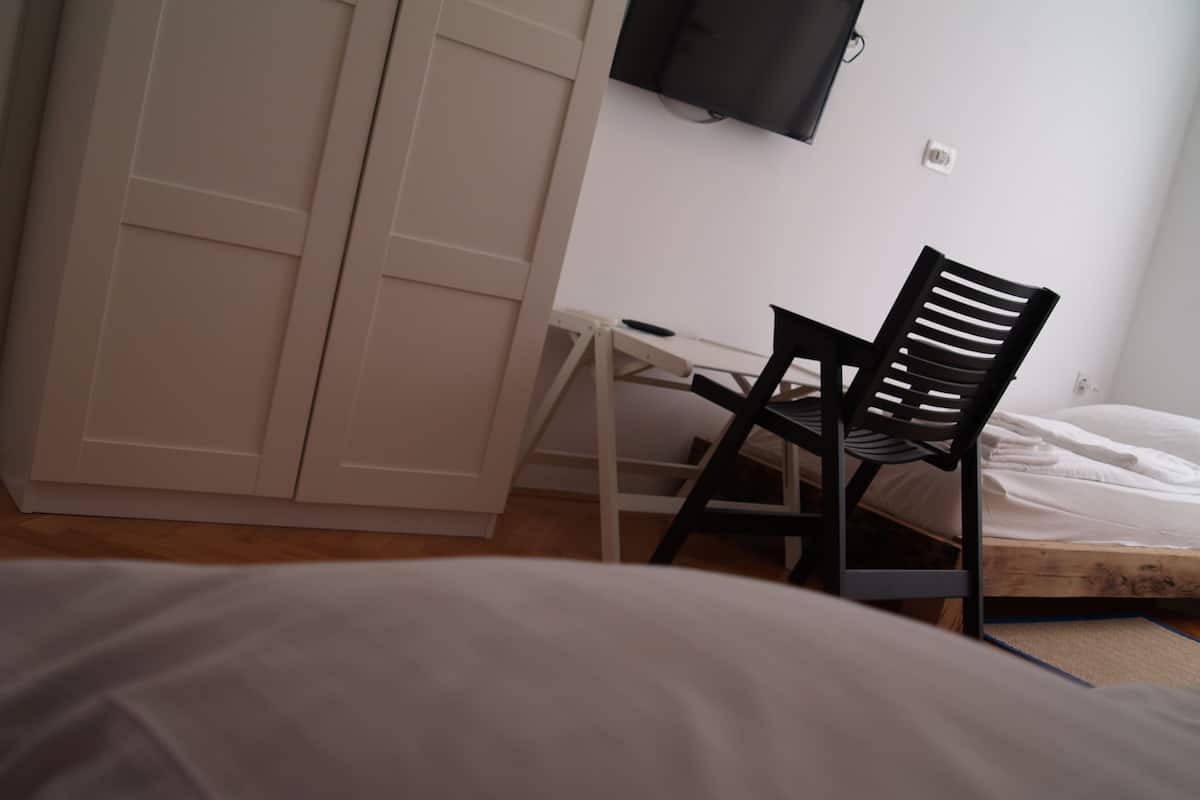 A bedroom with a bed, a desk, a chair, and a wardrobe.
