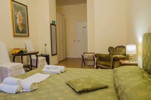 A hotel room with a bed, a chair, a table, and a lamp.