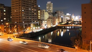 A nighttime cityscape with a river, high-rise buildings, and a bridge. - Guesthouse SUN - Hostel (Osaka)