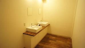 A bathroom with two sinks, wooden countertop, and a mirror. - Guesthouse SUN - Hostel (Osaka)