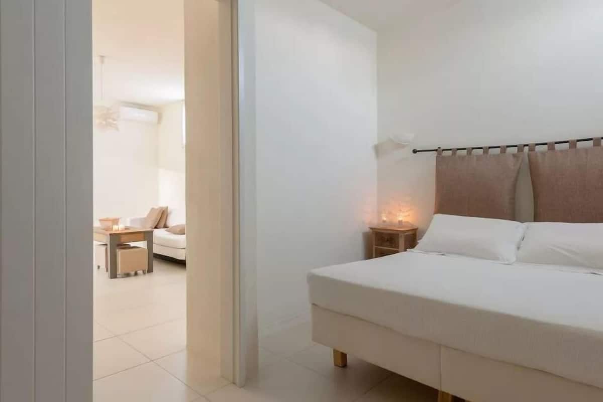 A bedroom with a bed, bedside table, and a nightstand with a lamp.