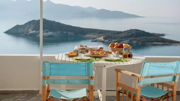 A table set with breakfast items and a view of a mountainous coastline. - Kimolia Gi Studios (Kimolos)