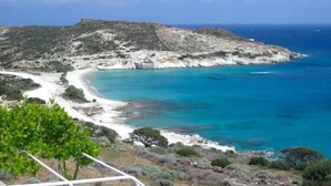 A coastal landscape with a clear view of the sea, rocky terrain, and a small beach area. - Kimolia Gi Studios (Kimolos)
