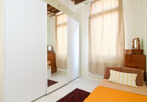 Un dormitorio con cama, cómoda, espejo y radiador.