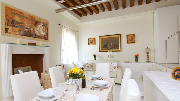 A dining room with a white table set for six, a fireplace, and a painting on the wall. - Venezia Gentile (Venice)