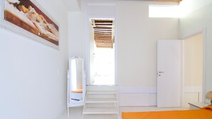 A bedroom with a bed, a wardrobe, a mirror, and a staircase leading to an upper level. - Venezia Gentile (Venice)
