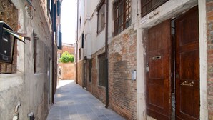 A narrow alleyway with stone pavement, wooden doors, and brick walls. - Venezia Gentile (Venice)