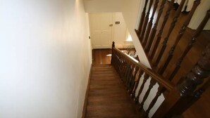 A wooden staircase with a handrail, leading to a white door at the top. - Annies Garden Cottage (South Hobart)