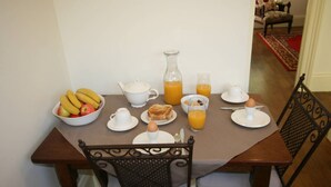 A dining table set with breakfast items including fruits, eggs, toast, and orange juice. - Annies Garden Cottage (South Hobart)