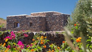 Um edifício de pedra com uma pequena janela, rodeado por flores vibrantes.