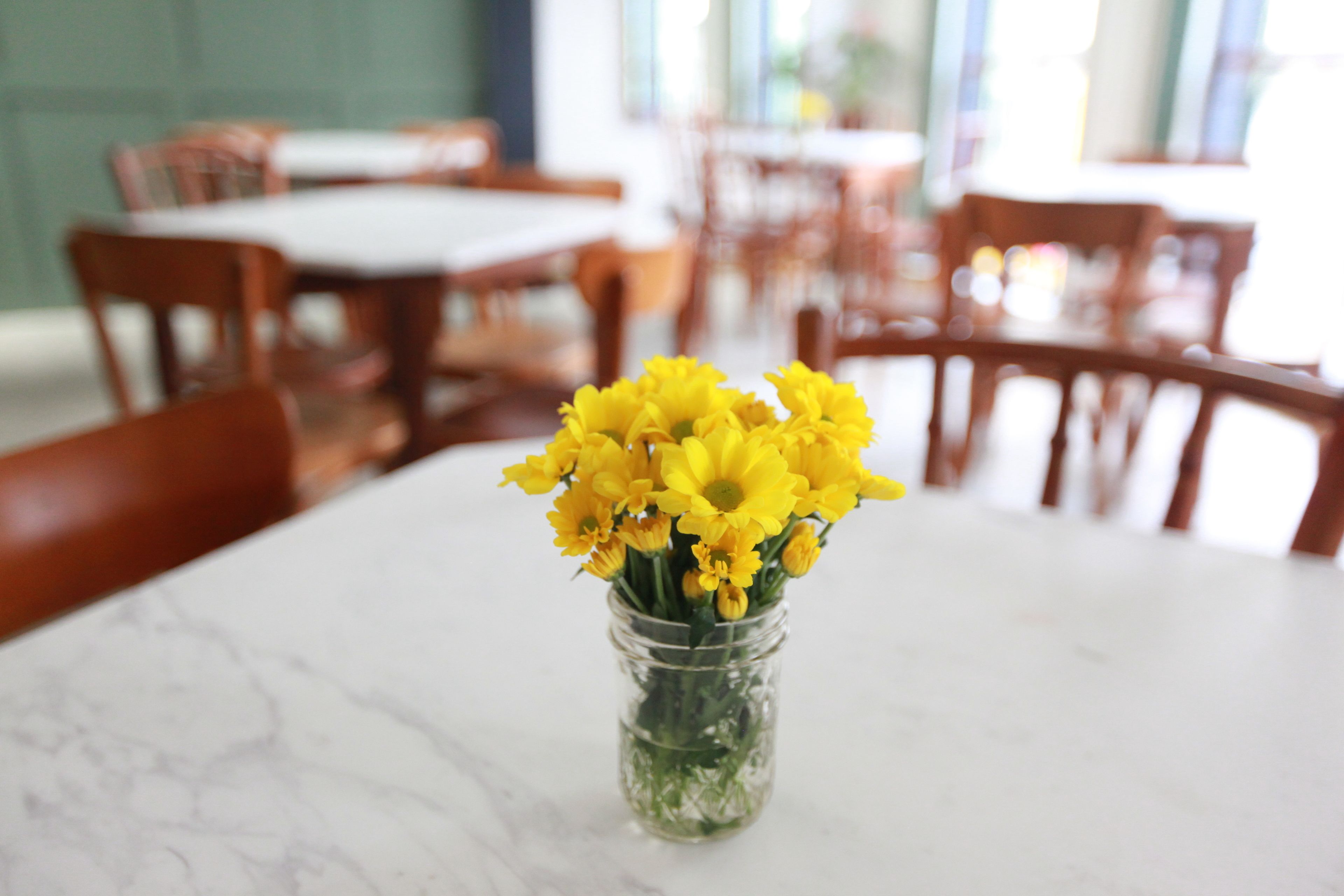 A marble table with a clear glass vase containing yellow flowers.