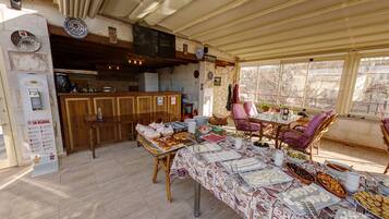 A dining area with a buffet setup, wooden furniture, and a view through large windows.