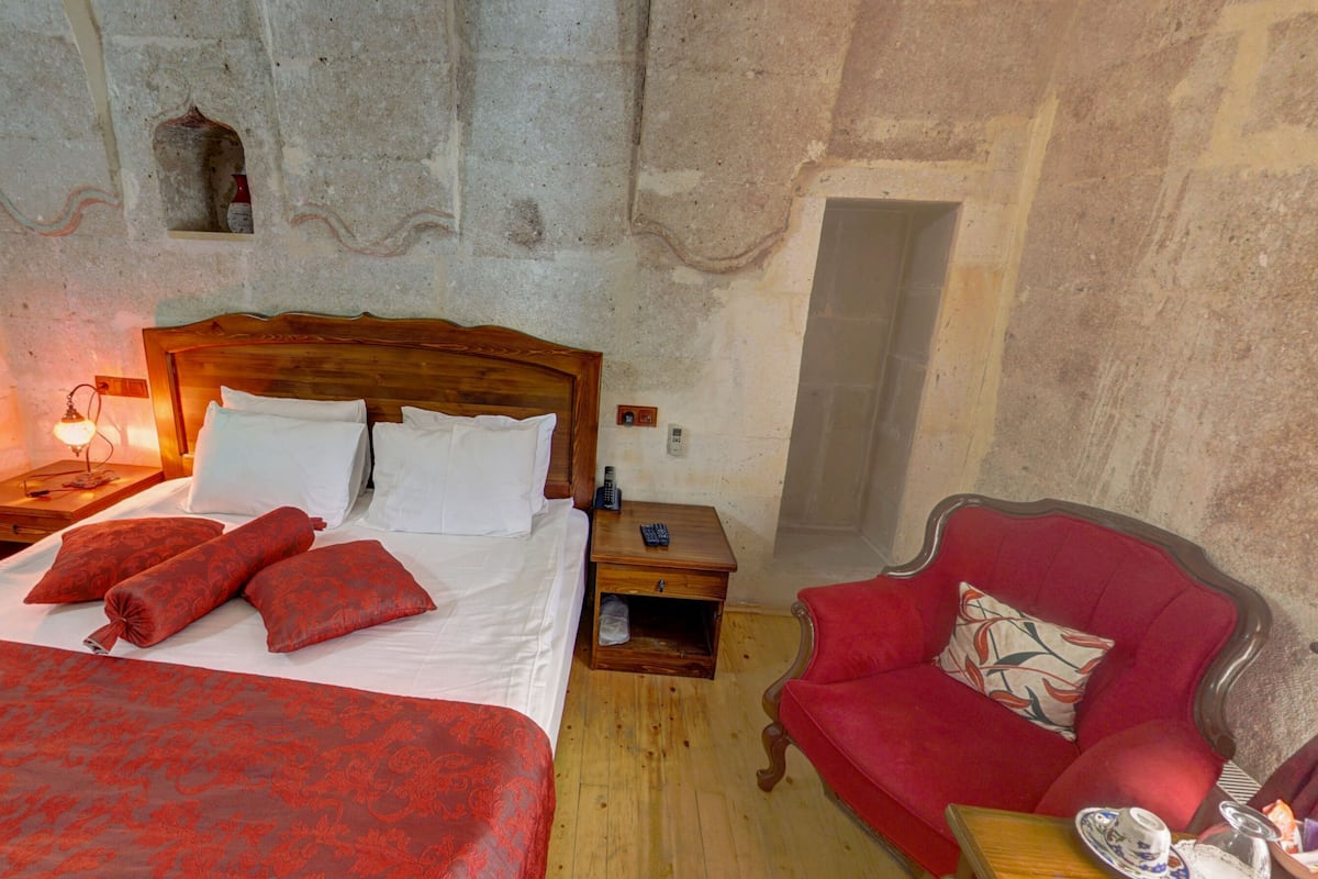 Une chambre à coucher avec un lit en bois, une chaise rouge et une table de chevet avec une lampe.