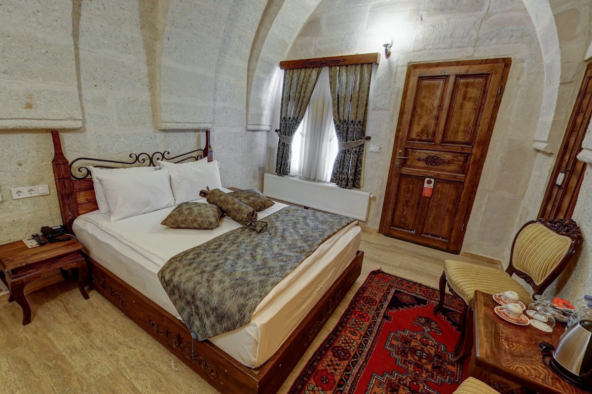 Une chambre à coucher comprenant un lit, une table de chevet, une armoire et une fenêtre avec des rideaux.