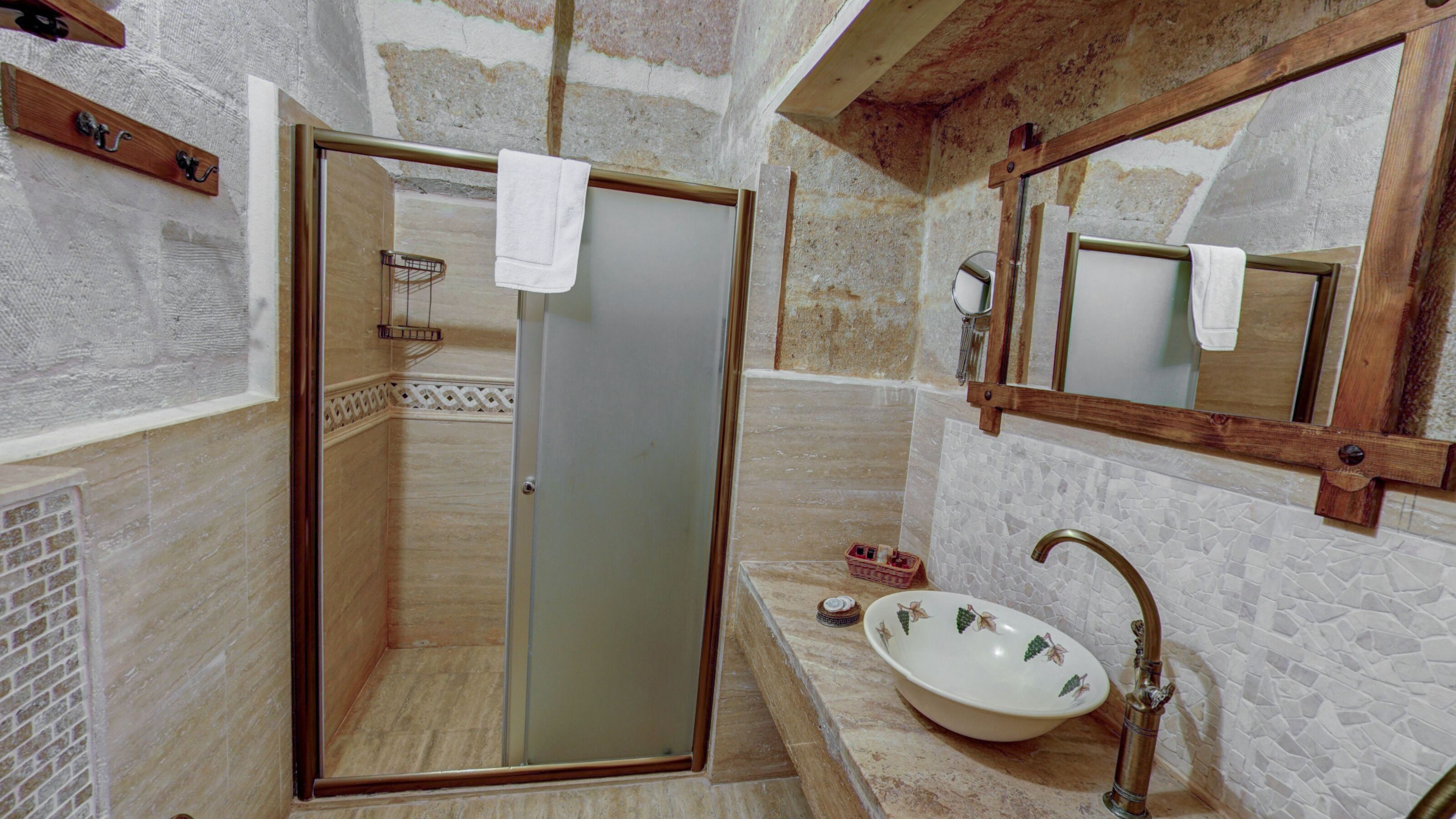A bathroom with a glass door shower, a sink with a mosaic backsplash, and a wooden-framed mirror.