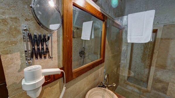 A bathroom with a hairdryer, a mirror, and a shower area. - Hikmet's House (Avanos)