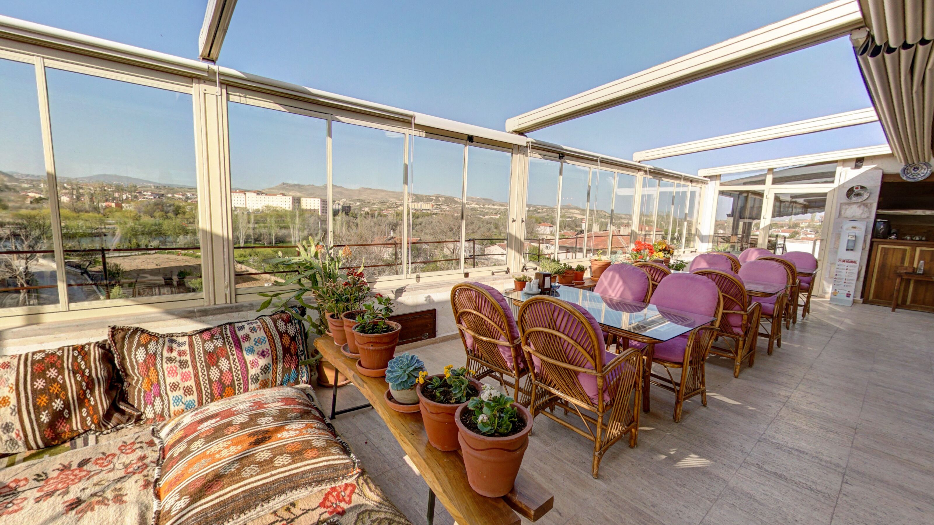 A spacious balcony with a sofa, chairs, and potted plants.