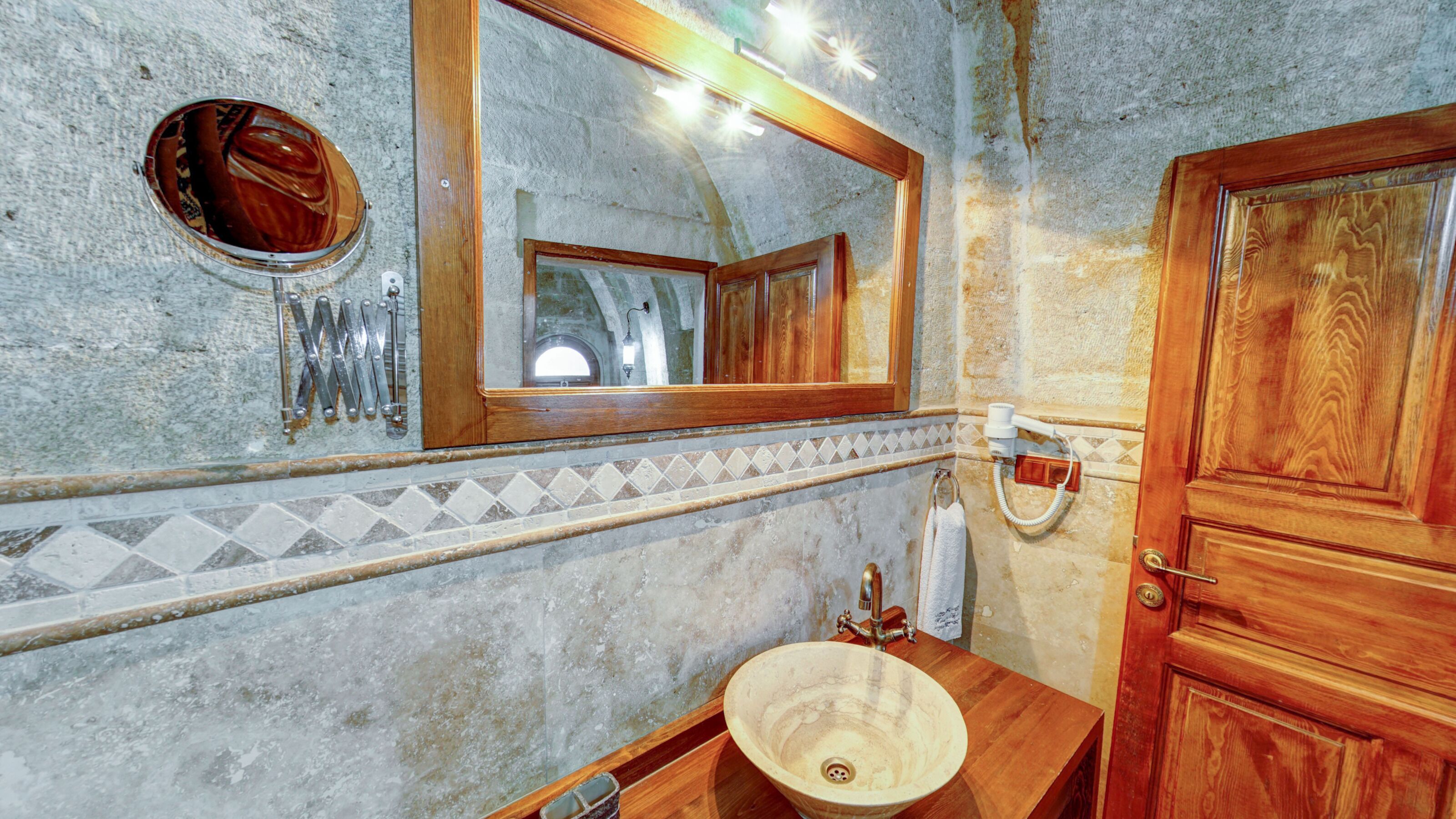 A bathroom with a wooden vanity, a large mirror, and a towel rack.