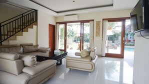 A spacious living room with a beige sofa, a coffee table, and a staircase.