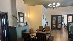A spacious living room with a wooden floor, a dining area with a table and chairs, a chandelier, and a large mirror on the wall. - Jubilee Hotel (Troodos)