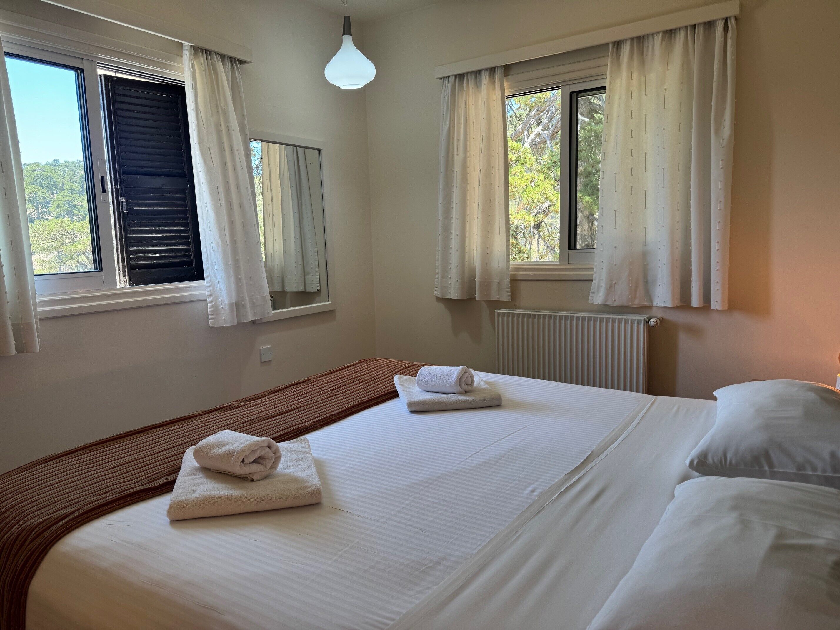 Une chambre d’hôtel avec deux lits, un radiateur et des fenêtres équipées de rideaux.