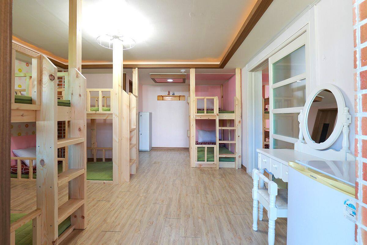 A children's playroom with bunk beds, a vanity with a mirror, and a refrigerator.