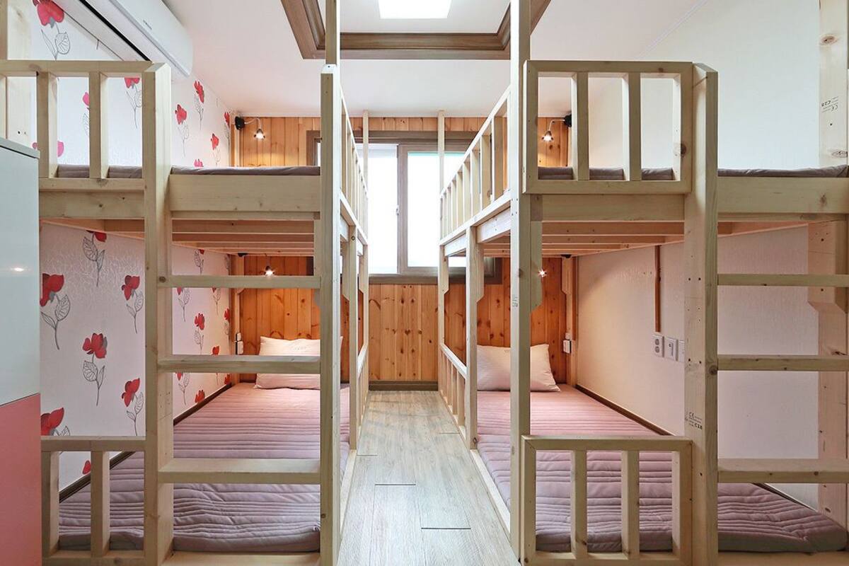 A bunk bed room with wooden frames and a central walkway.