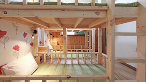 Une chambre avec un lit superposé, un plafond en bois, un matelas vert et un oreiller blanc.
