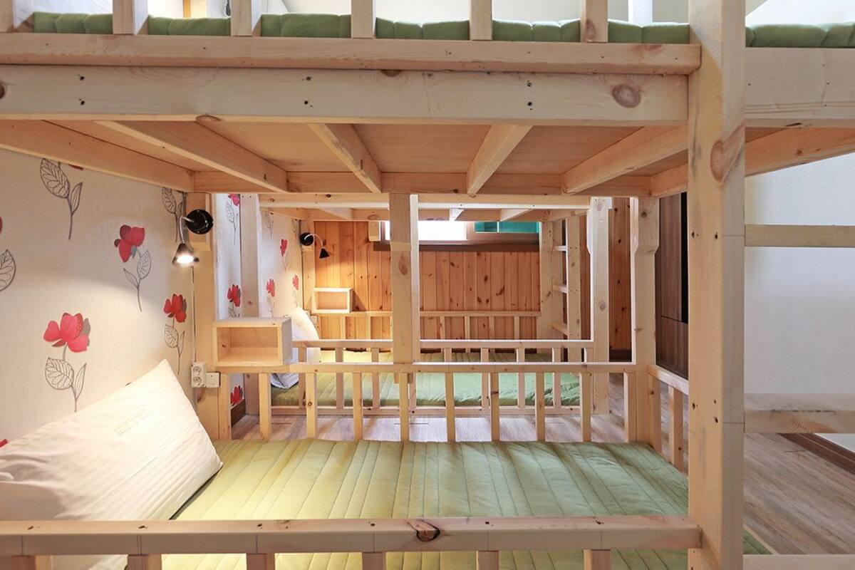 A bunk bed room with a wooden ceiling, a green mattress, and a white pillow.