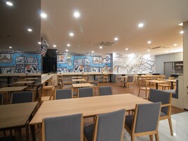 Un restaurante con mesas y sillas de madera, un mural en la pared y un mapa.