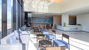 A modern hotel lobby with a reception desk, seating area, and a mural. - Fortune D Hotel Phitsanulok (Phitsanulok)
