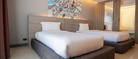 Une chambre d’hôtel avec deux lits, un grand miroir et une carte géographique accrochée au mur.