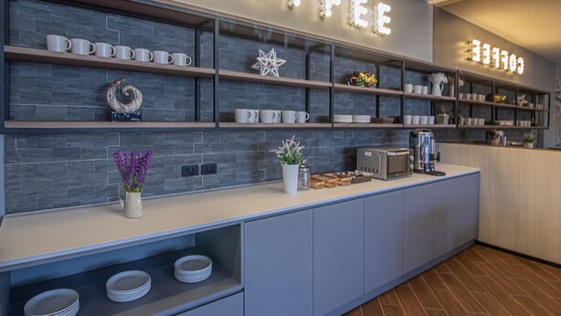A modern coffee bar with a 'COFFEE' sign, shelves with mugs, a star decoration, and a toaster. - Fortune D Hotel Phitsanulok (Phitsanulok)